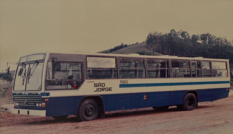 Ônibus antigo da São Jorge, número 560, parado em estrada de terra com morros ao fundo.