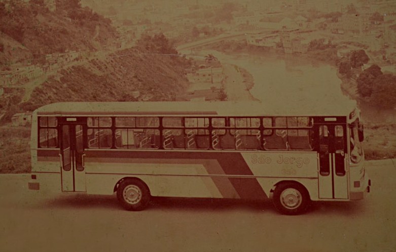 Ônibus antigo da São Jorge visto de lado, em área rural.